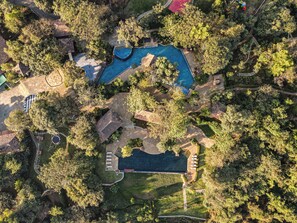 An aerial view of a resort with multiple swimming pools, a tennis court, and lush greenery. - Club Mahindra Resort - Tungi (Mawal)