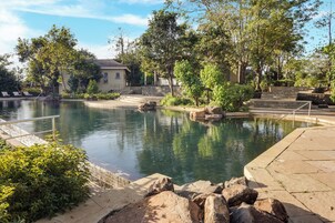 Un espace piscine extérieur paisible, doté d’une terrasse en pierre, de chaises longues et d’un escalier en pierre menant à un bâtiment.