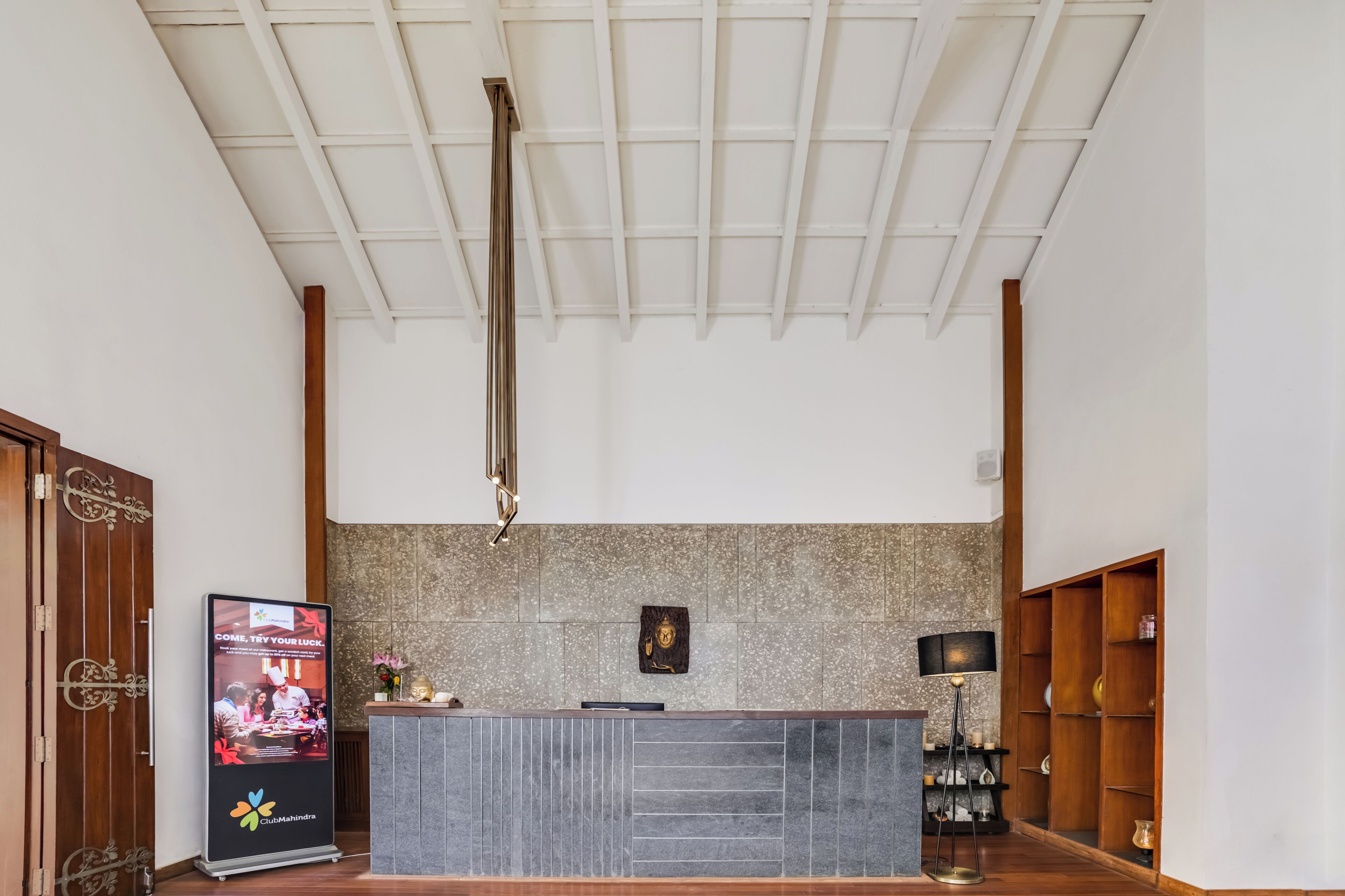 A reception desk with a modern design, a ceiling with a grid pattern, and a wall with a speckled tile backsplash.