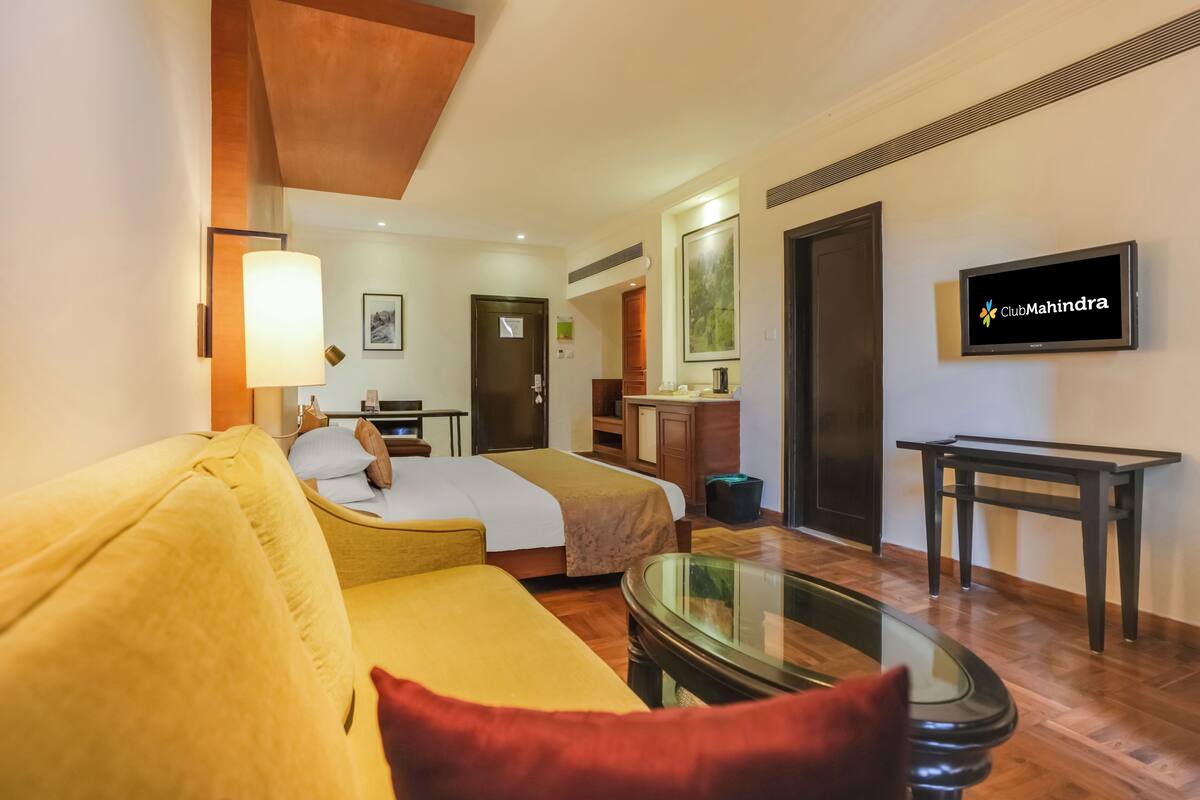 A hotel room with a bed, a sofa, a TV, and a desk.