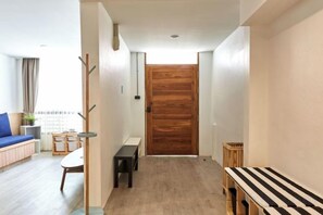 A hallway with a wooden door, a bench, and a small table. - Vann House Hua Hin (Hua Hin)