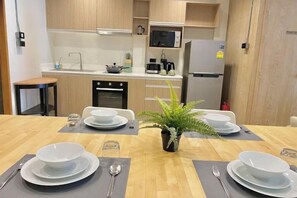 Une cuisine moderne avec une table à manger mise pour quatre personnes, comprenant des assiettes, des couverts et une plante en pot.