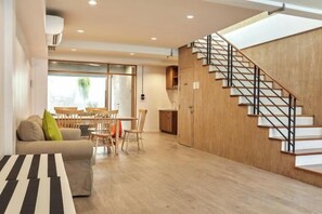 A modern interior with a staircase, a dining area, and a sofa. - Vann House Hua Hin (Hua Hin)