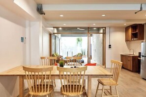 Une cuisine moderne avec des meubles en bois, une table à manger avec des chaises et une vue à travers une porte vitrée.