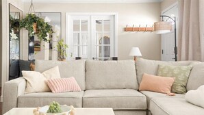 A living room with a sectional sofa, a coffee table with a plant, and a hanging plant above a mirror. - Family Resort: Pool & Outdoor Theater near Old Town, Golf, Baseball, and Events (Scottsdale)