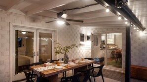 A dining area with a long table set for six, surrounded by black chairs. There is a ceiling fan above and a vase with flowers on the table. - Family Resort: Pool & Outdoor Theater near Old Town, Golf, Baseball, and Events (Scottsdale)