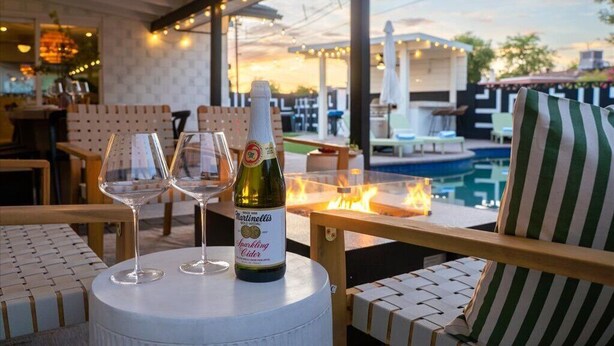 An outdoor seating area with a pool, a bottle of Martinielli Sparkling Cider, and two glasses. - Family Resort: Pool & Outdoor Theater near Old Town, Golf, Baseball, and Events (Scottsdale)