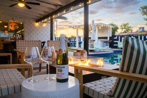 Zona d'estar a l'aire lliure amb una piscina, una ampolla de Martinielli Sparkling Cider i dues copes.