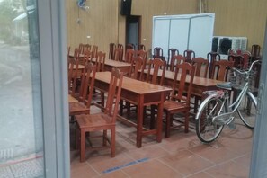 A dining area with wooden tables and chairs, a bicycle, and a whiteboard.