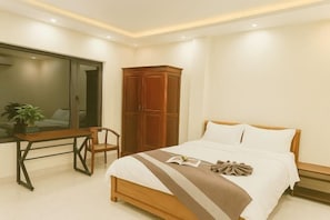 A bedroom with a bed, a wooden wardrobe, a desk with a chair, and a large mirror. - MingFang Hotel (Bac Ninh)