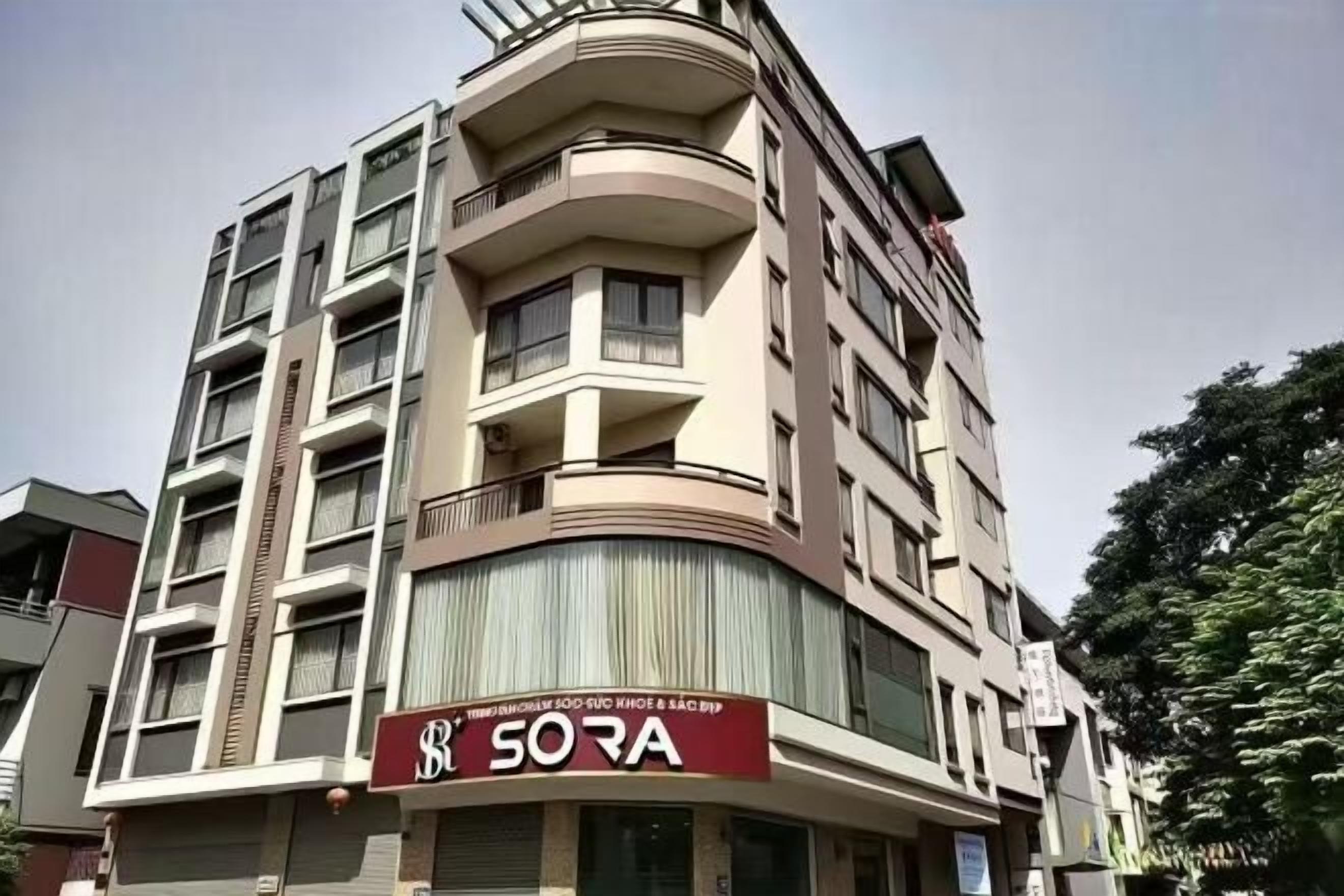 Un immeuble à plusieurs étages, avec une grande enseigne « SORA » bien visible au rez-de-chaussée.