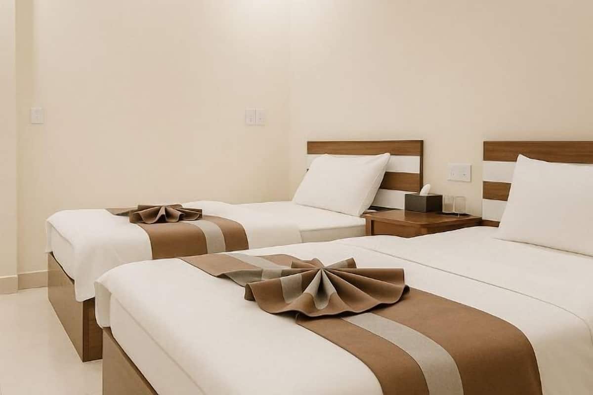 A hotel room with two beds, each with a wooden headboard, white bedding, and decorative pillows.