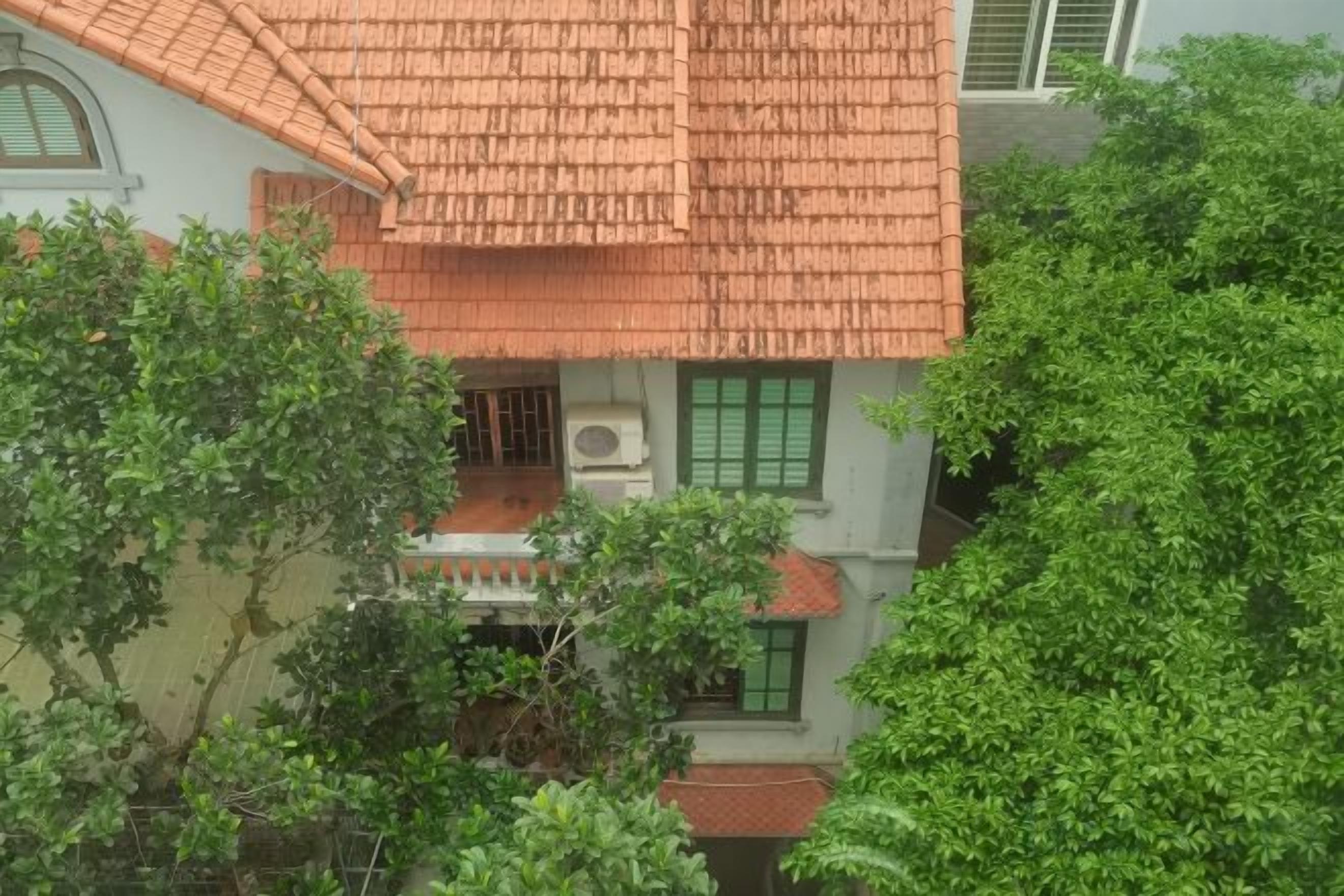 Um edifício com telhado em telhas, persianas verdes e uma varanda.