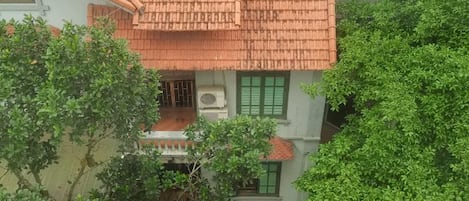 A building with a tiled roof, green shutters, and a balcony.