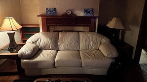 Una sala de estar con un sofá color beige, una repisa de madera y dos lámparas fijadas a la pared.