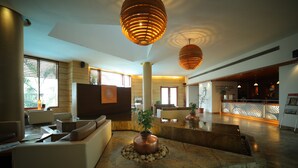 Un'ampia hall con un'area salotto centrale, una reception e un'elegante fontana decorativa.