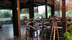 Des vélos sont garés sur un porte-vélos dans un espace extérieur abrité, avec vue sur la verdure.