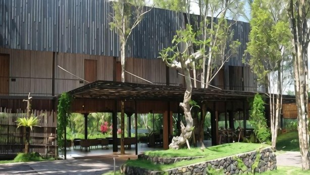 Un bâtiment moderne doté d’un espace extérieur aménagé avec une terrasse couverte, d’un chemin en pierre et de verdure.