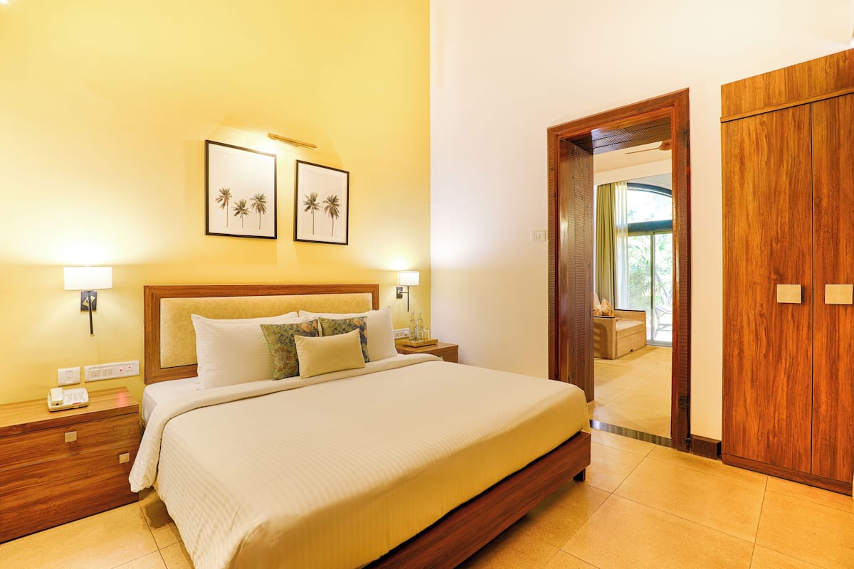 A hotel room with a large bed, wooden headboard, bedside lamps, and framed artwork on the wall.