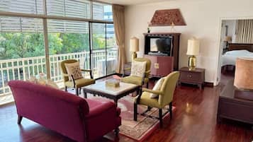 A hotel room with a balcony, a TV, a bed, and a seating area with a table and chairs.