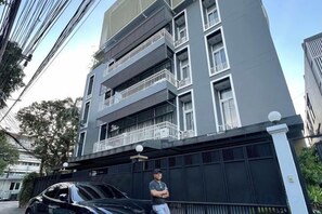 A multi-story building with balconies, a gated entrance, and a parked car. - Samsen Suites (Bangkok)