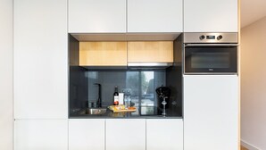 Eine moderne Küche mit weißen Schränken, einem eingebauten Backofen und einem Fenster.