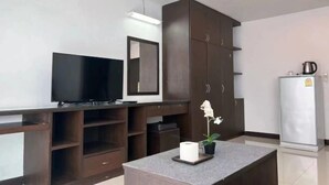 A modern kitchen with a built-in TV, a large cabinet, a refrigerator, and a small table with a plant. - Tongyang House Serviced Apartment (Bangkok)