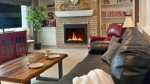 A living room with a fireplace, leather sofa, and a television.