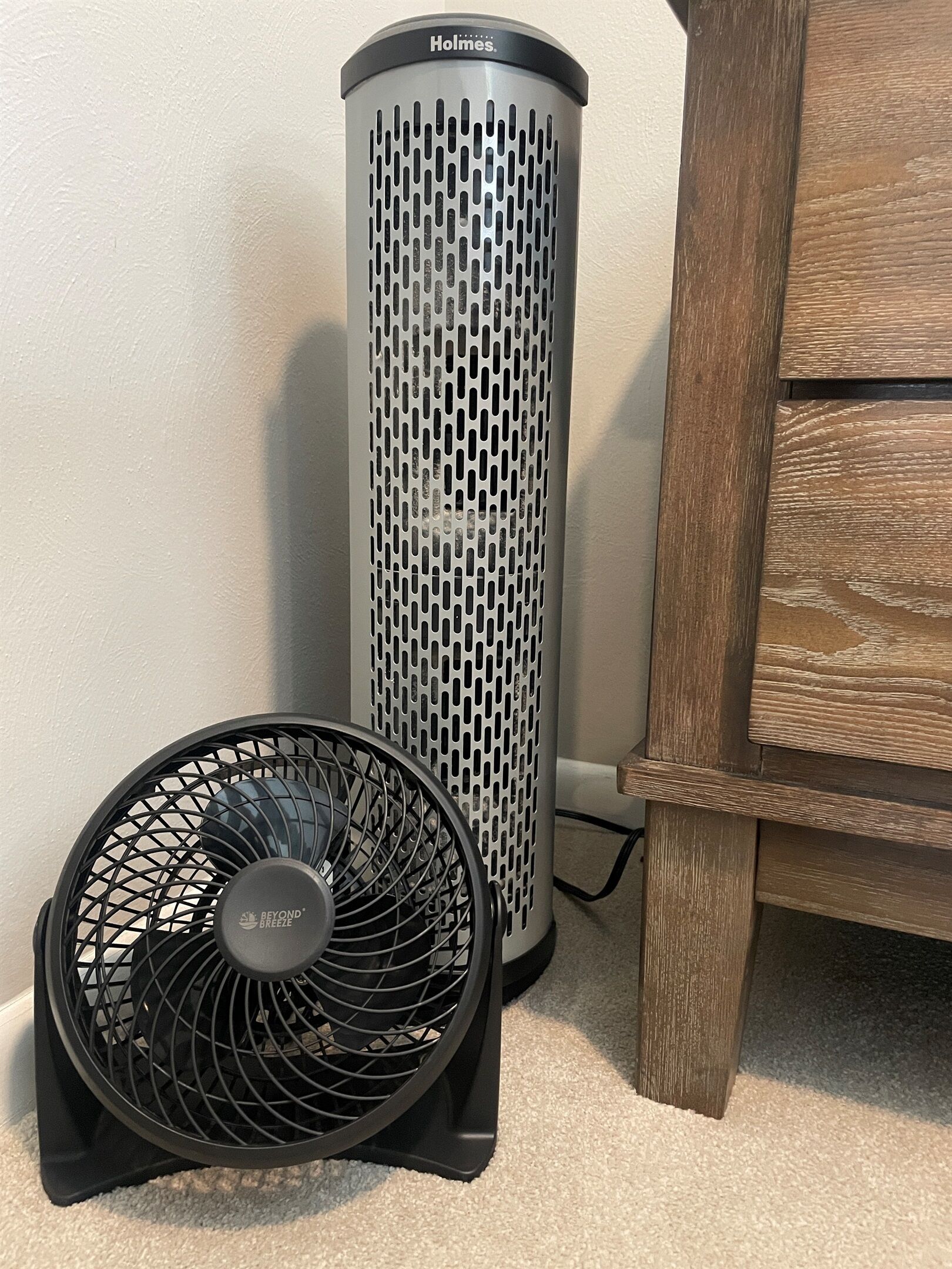 A cylindrical device with a perforated design, a fan with a circular grill, and a wooden cabinet.