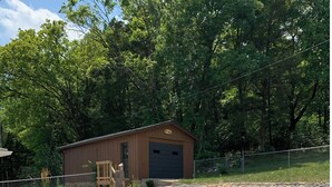 A backyard with a barbecue area, a wooden shed, and a landscaped garden with stepping stones and plants.