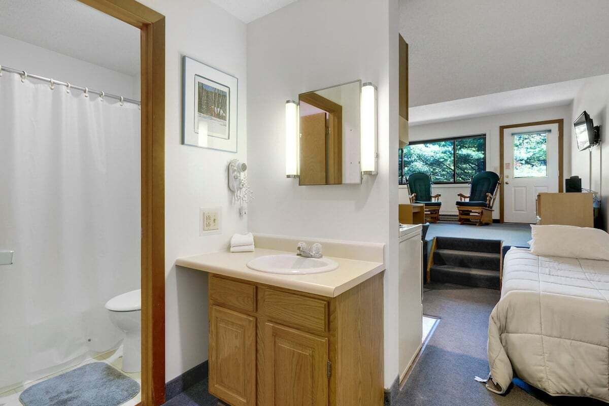 A bathroom with a shower, toilet, sink, and mirror.