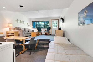 A modern, well-lit room with a sofa, a dining table, and a bed.
