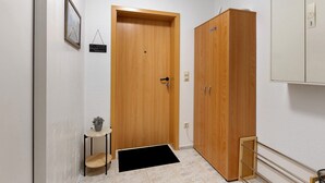 A hallway with a wooden door, a small table with a plant, and a cabinet. - Apartment 'Ketterer' with Terrace, Garden and Wi-Fi (Hüfingen)