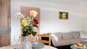 A dining table with a vase of flowers, a wine glass, and plates. - Apartment 'Ketterer' with Terrace, Garden and Wi-Fi (Hüfingen)