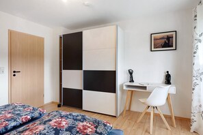 A bedroom with a bed, a desk, a chair, a wardrobe, and a picture on the wall. - Apartment 'Ketterer' with Terrace, Garden and Wi-Fi (Hüfingen)