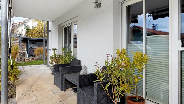 A covered outdoor seating area with wicker furniture, potted plants, and a view of the neighborhood. - Apartment 'Ketterer' with Terrace, Garden and Wi-Fi (Hüfingen)
