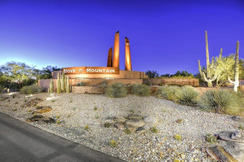 A building with the sign 'DOVE MOUNTAIN' and a desert landscape with cacti.