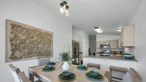 A modern kitchen with stainless steel appliances, a central island, and a dining area with a large table set for six.
