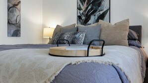 A neatly made bed with a patterned bedspread, multiple pillows, and a bedside table with a tray.