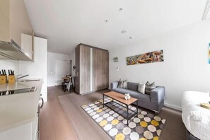 Un appartement moderne comprenant une cuisine, un espace de vie avec un canapé et une table basse, et une chambre avec un lit.