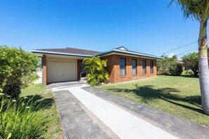 A single-story house with a garage, a front lawn, and a palm tree.