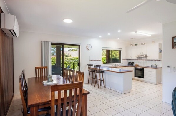 A modern kitchen with white cabinets, a central island, and a dining area with wooden chairs.