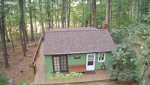 Une petite cabane avec un toit en pente, une porte d’entrée et un petit espace de véranda.