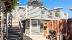 Een woonhuis met twee verdiepingen, een balkon, een houten trap en een barbecuehoek.