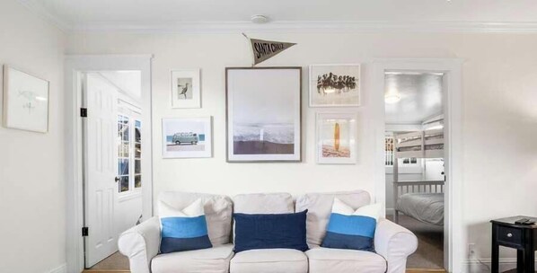 A living room with a white sofa, framed pictures on the wall, and a door leading to another room. - 3 Bedroom Home Near Twin Lakes Beach (Santa Cruz)