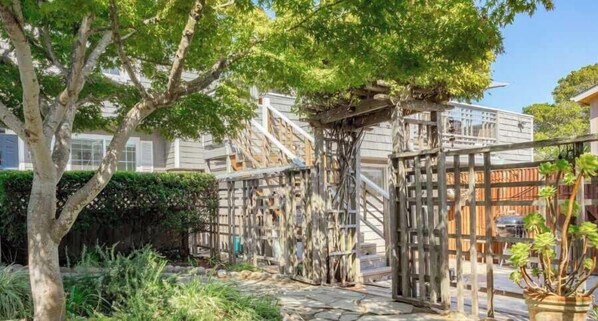 A shared outdoor space with a wooden pergola, stone pathway, and lush greenery.