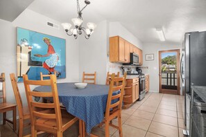 A dining area with a table set for four, wooden chairs, a blue tablecloth, and a painting on the wall. - Twin Lakes Surf Cabin - Sleeps Up To 12 (Santa Cruz)
