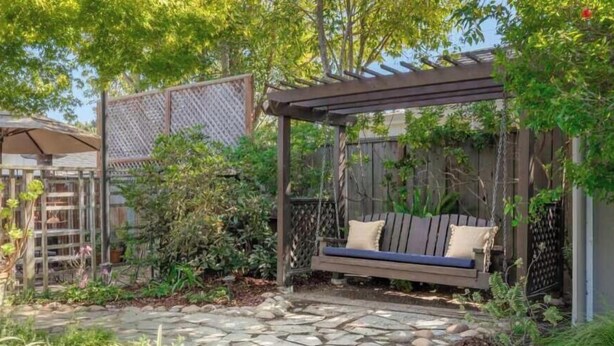 A shared outdoor space with a wooden swing, stone pathway, and lush greenery. - Twin Lakes Surf Cabin - Sleeps Up To 12 (Santa Cruz)