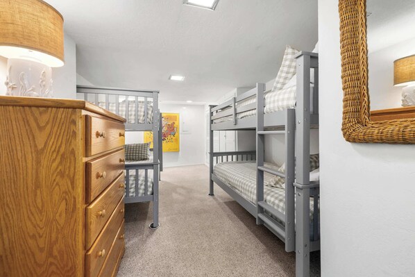 Un dormitorio con literas, un aparador de madera y una lámpara de pared.