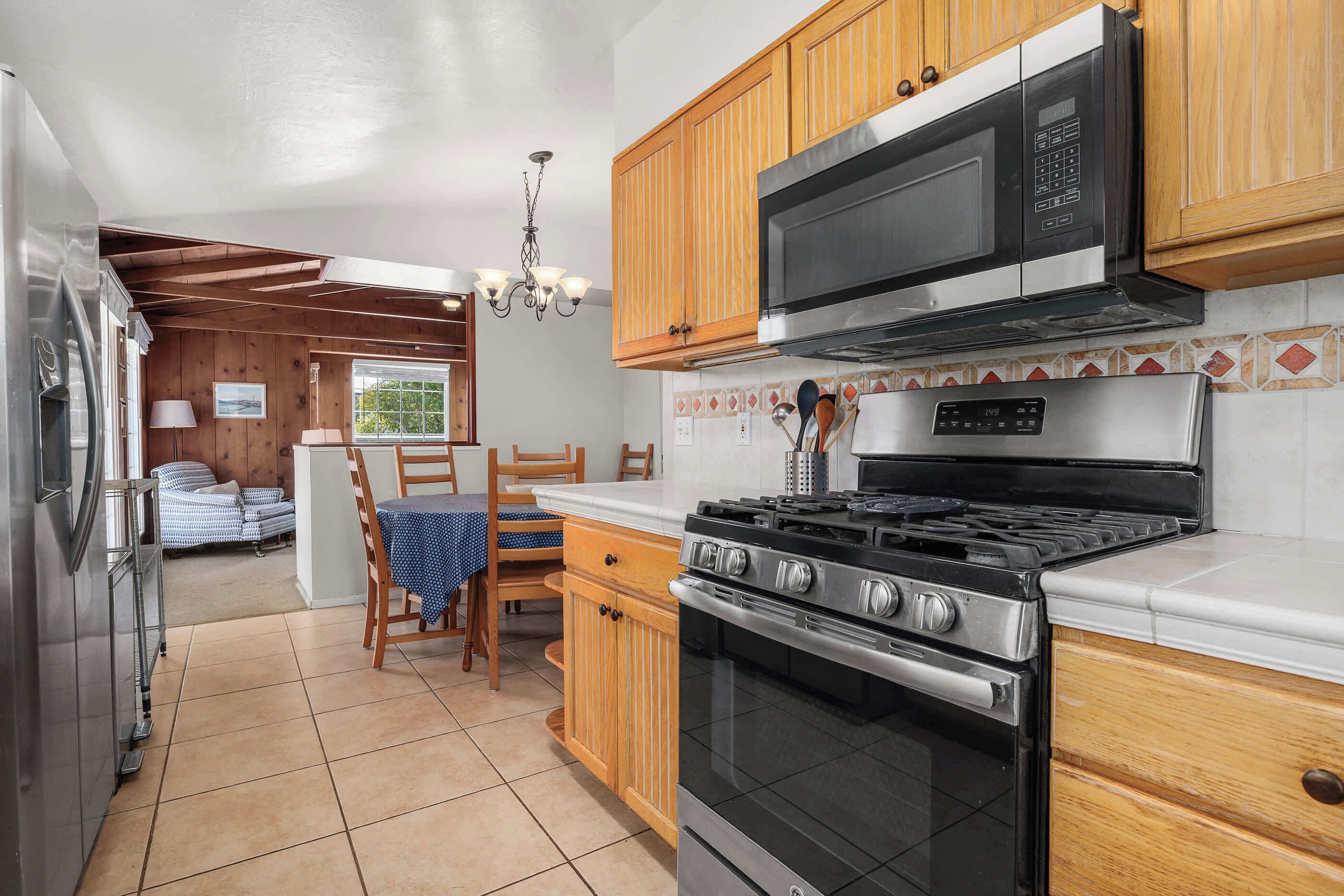 Una cocina con muebles de madera, estufa de acero inoxidable y microondas.